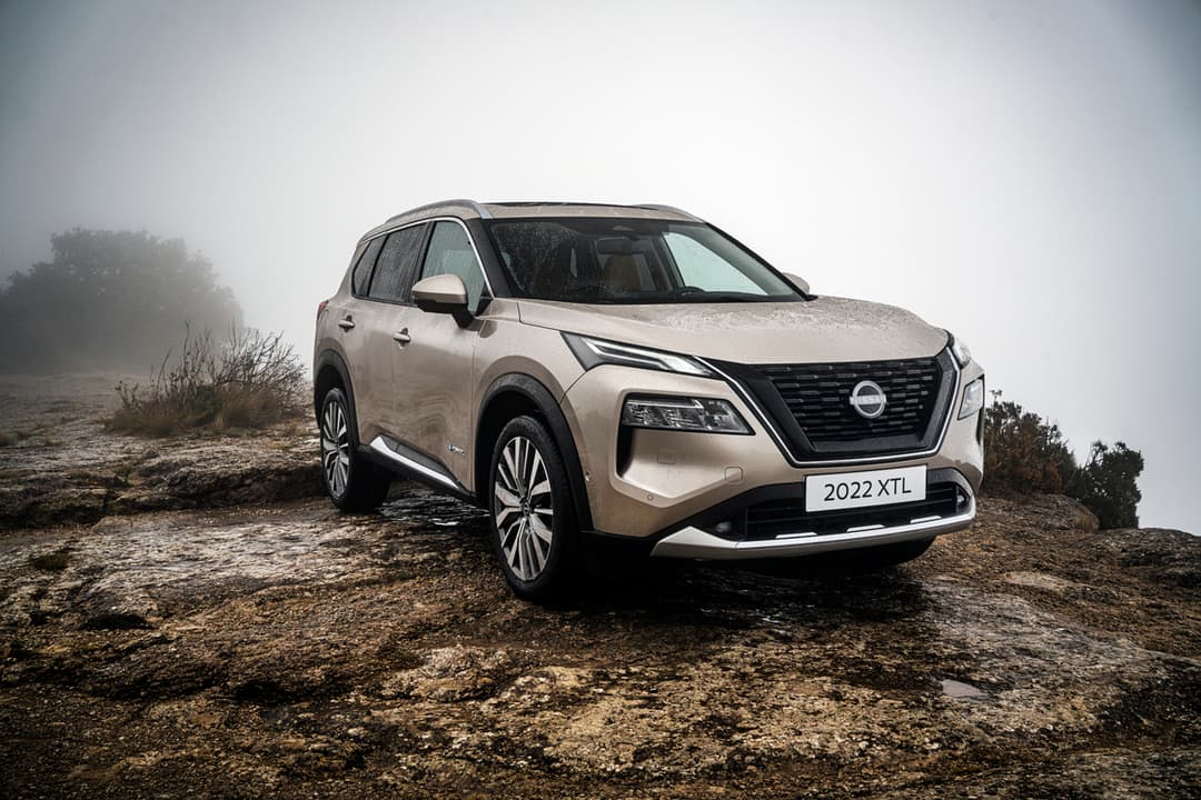 Nissan X-Trail beige de quatrième génération stationné sur un terrain rocheux, par temps brumeux
