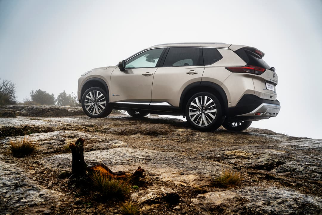 Nissan X-Trail blanc sur un terrain rocheux accidenté, vue de profil