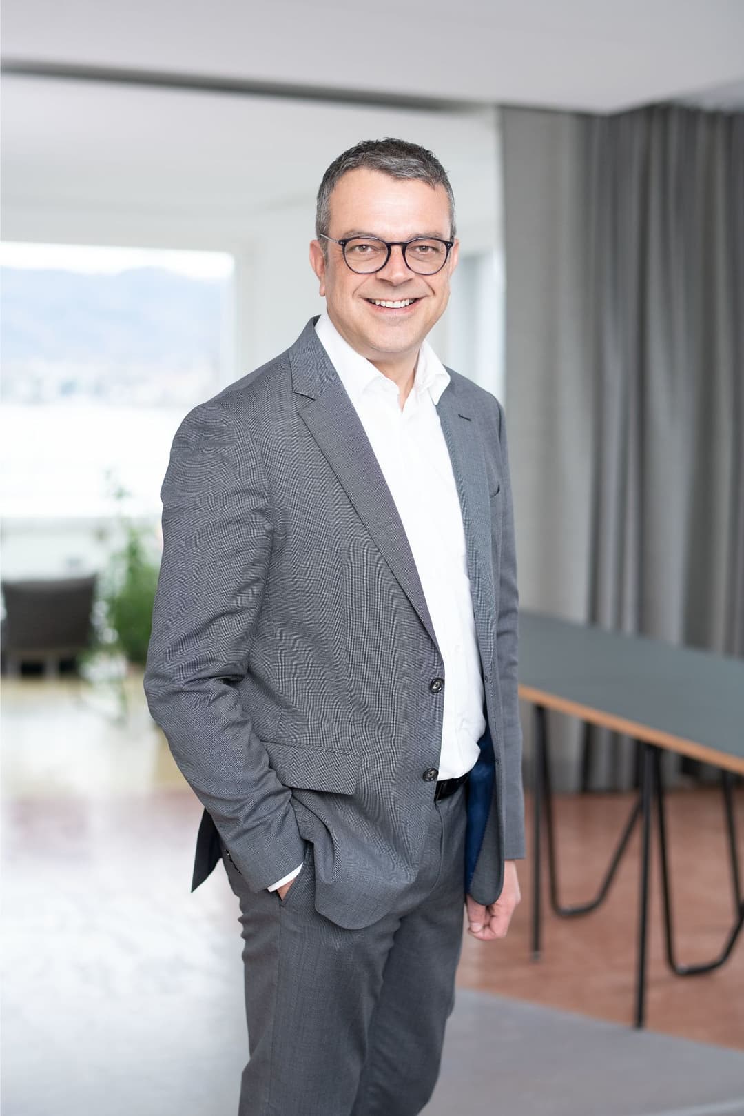 Daniel Meier, General Manager d'OPPO Suisse, en costume gris et chemise blanche dans un bureau moderne