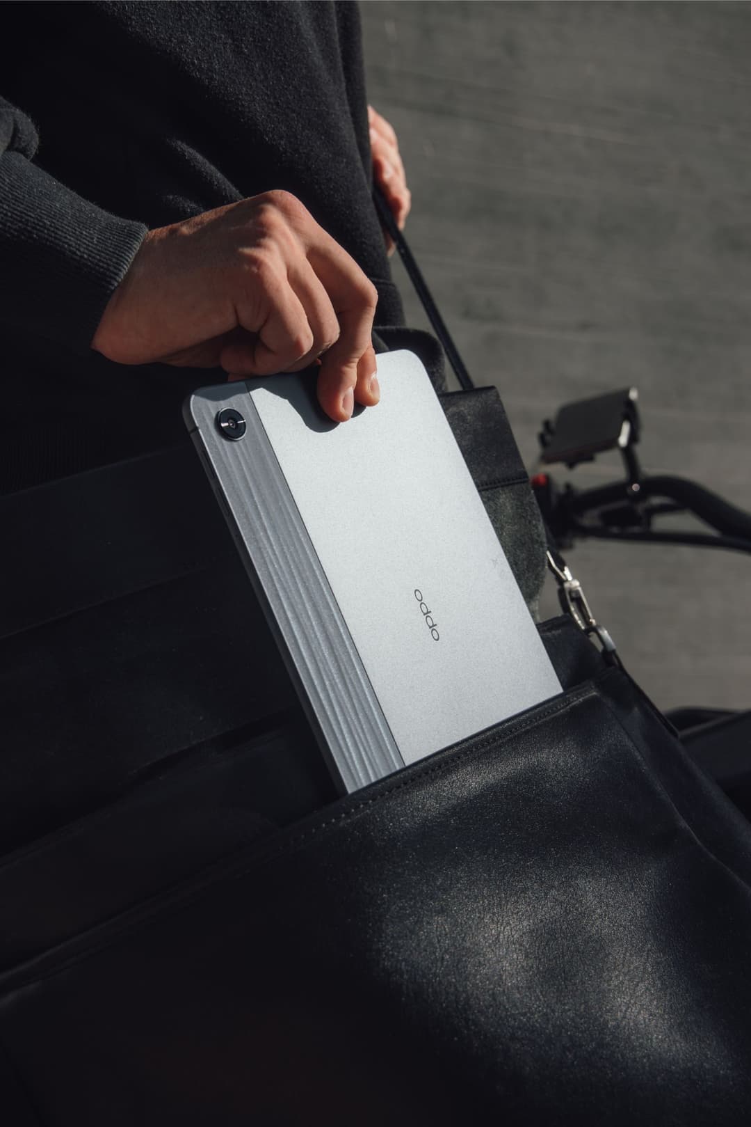 OPPO Pad Air blanc avec finition texturée, tenu par une main dans un sac noir