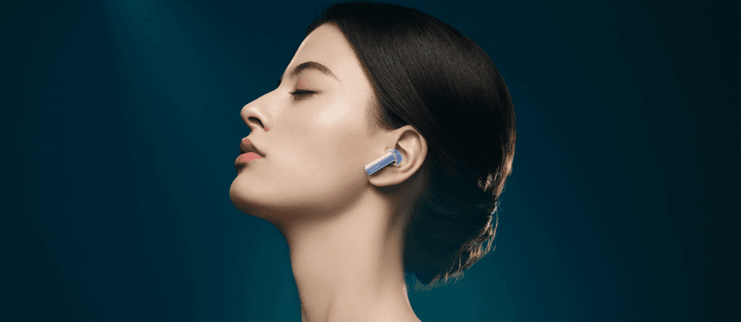 Écouteur Huawei FreeBuds Pro 2 bleu porté à l'oreille d'une femme de profil, sur fond bleu-vert