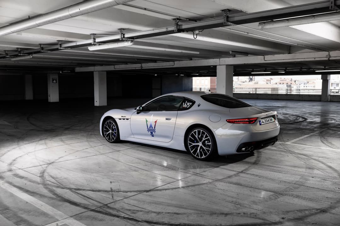 Maserati GranTurismo blanche garée dans un parking souterrain, logo du Trident sur la portière
