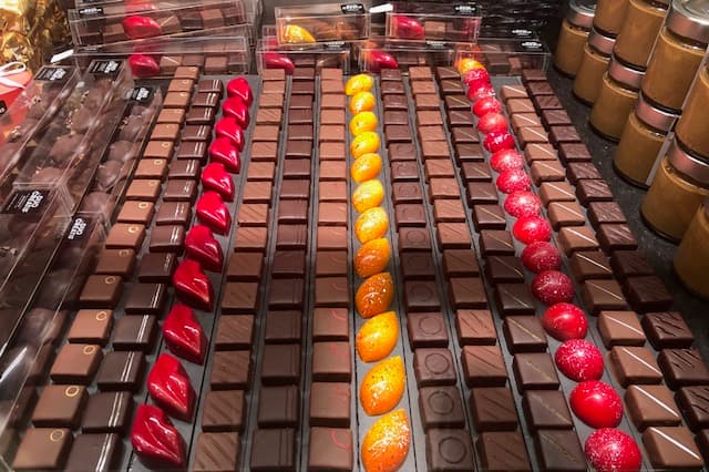 Rangées de chocolats et pralines colorés exposés dans des boîtes transparentes chez Duo Créatif, à la Tour-de-Peilz