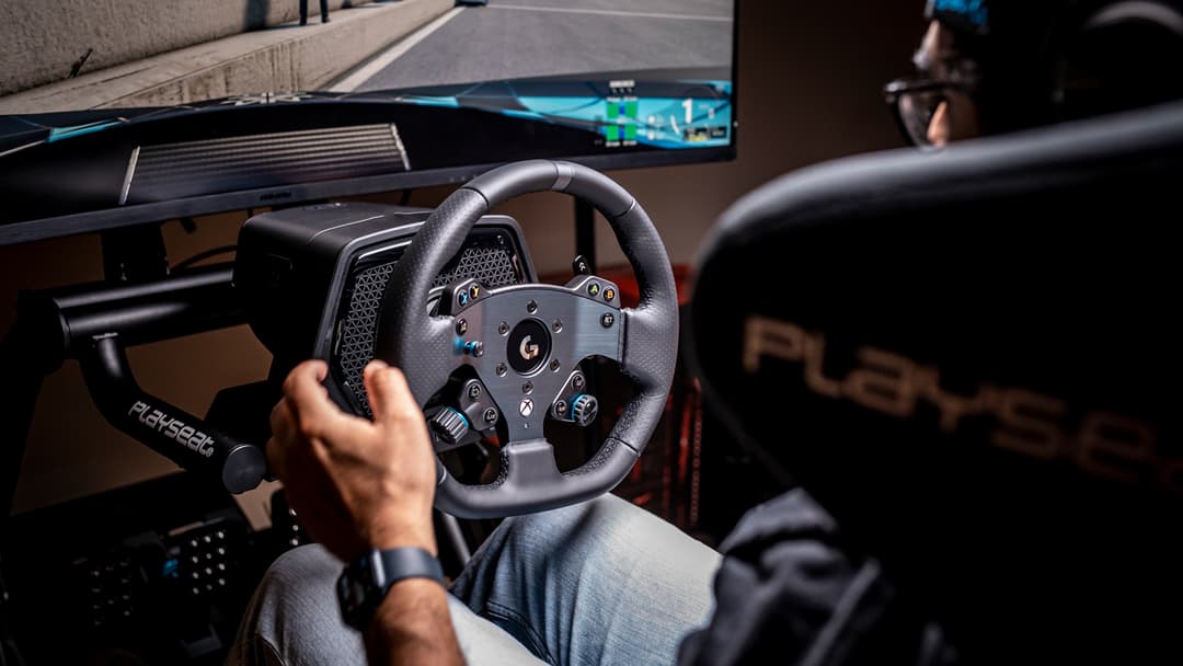 Logitech G PRO Racing : volant noir avec logo G tenu par un joueur assis face à un écran, en setup de simulation de course