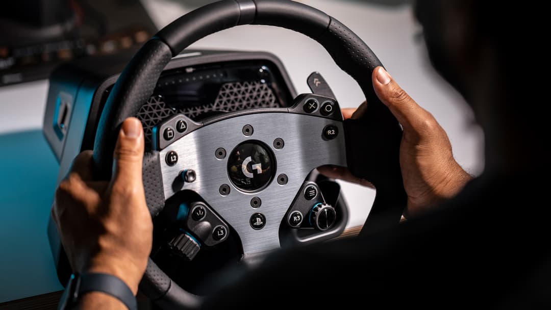 Volant de course Logitech G PRO Racing tenu en mains, avec écran de commandes et boutons pour PlayStation et Xbox