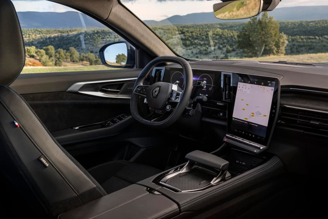 Intérieur du Renault Austral E-Tech full hybrid, vue du poste de conduite avec volant, écran tactile et paysage montagneux en arrière-plan