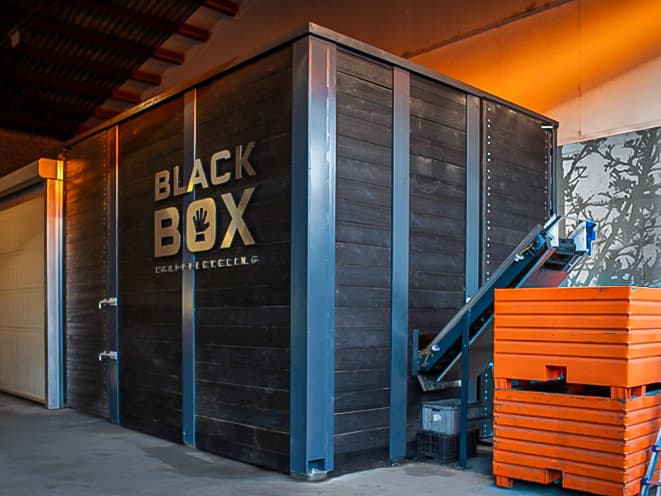 BLACK BOX, boîte noire de recyclage de toner par soRec, avec structure métallique et portes noires, accompagnée de bacs de collecte orange