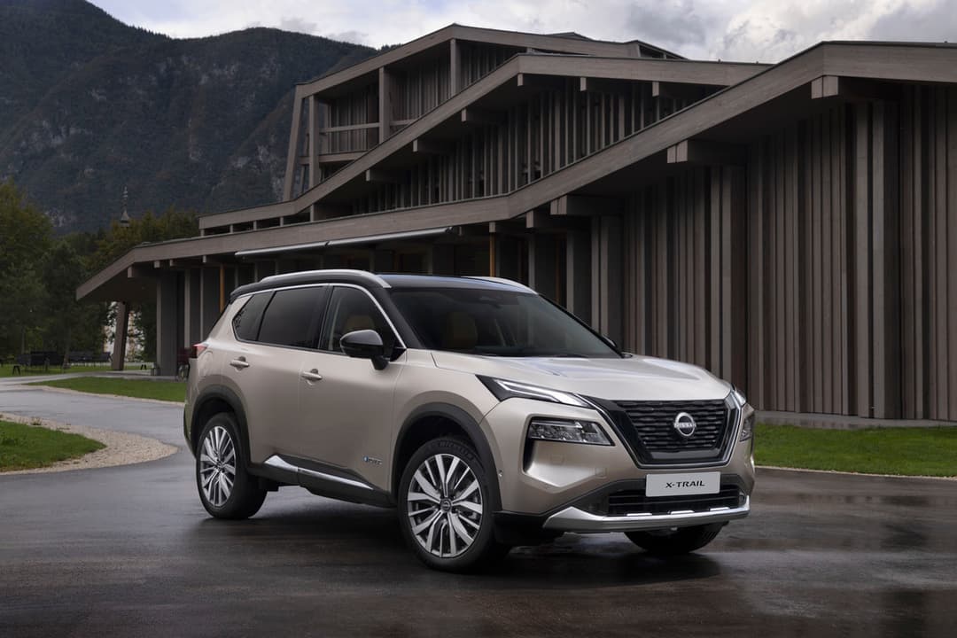 Nissan X-Trail blanc garé devant une structure architecturale moderne en montagne, vue de profil trois-quarts