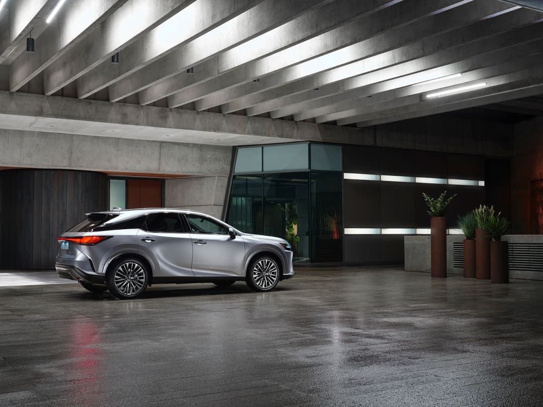 Lexus RX 450h+ gris métallisé garé dans un parking souterrain moderne aux structures bétonnées