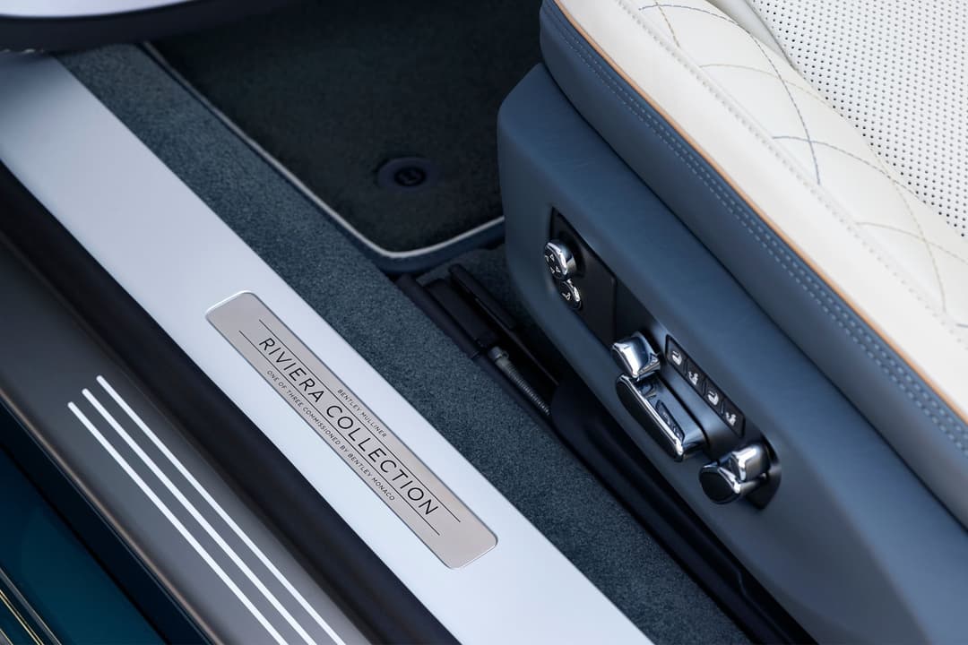 Intérieur de Bentley Mulliner Riviera Collection montrant la plaque de marche personnalisée, les sièges en cuir blanc avec coutures marines et l'appui-tête brodé