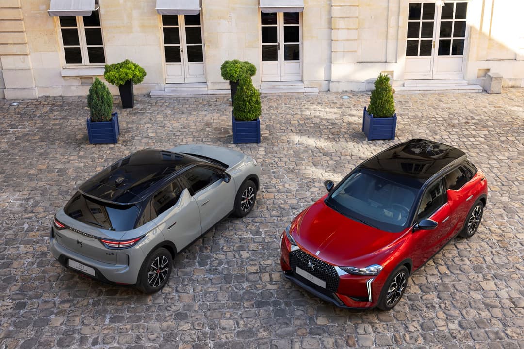 Deux DS 3 garées sur une cour pavée, l'une blanche et l'autre rouge, montrant la nouvelle calandre redessinée avec aerofoils