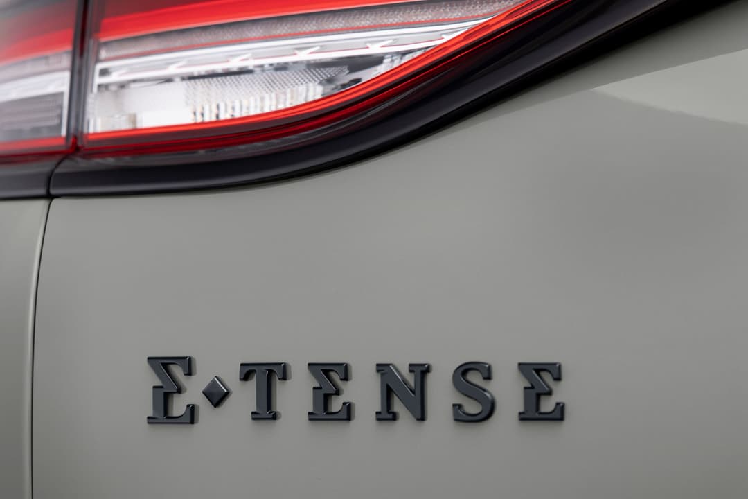 Détail du badging E-TENSE sur la carrosserie grise de la nouvelle DS 3 électrique, avec le feu arrière rouge distinctive