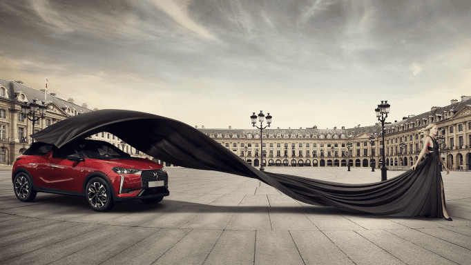 Nouvelle DS 3 rouge sur une place parisienne avec une femme tenant un voile noir dramatique