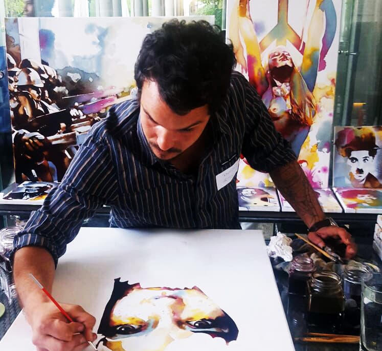 Sebastien Pridmore peint une toile abstraite aux couleurs vives, pinceau à la main, dans son atelier rempli d'œuvres colorées