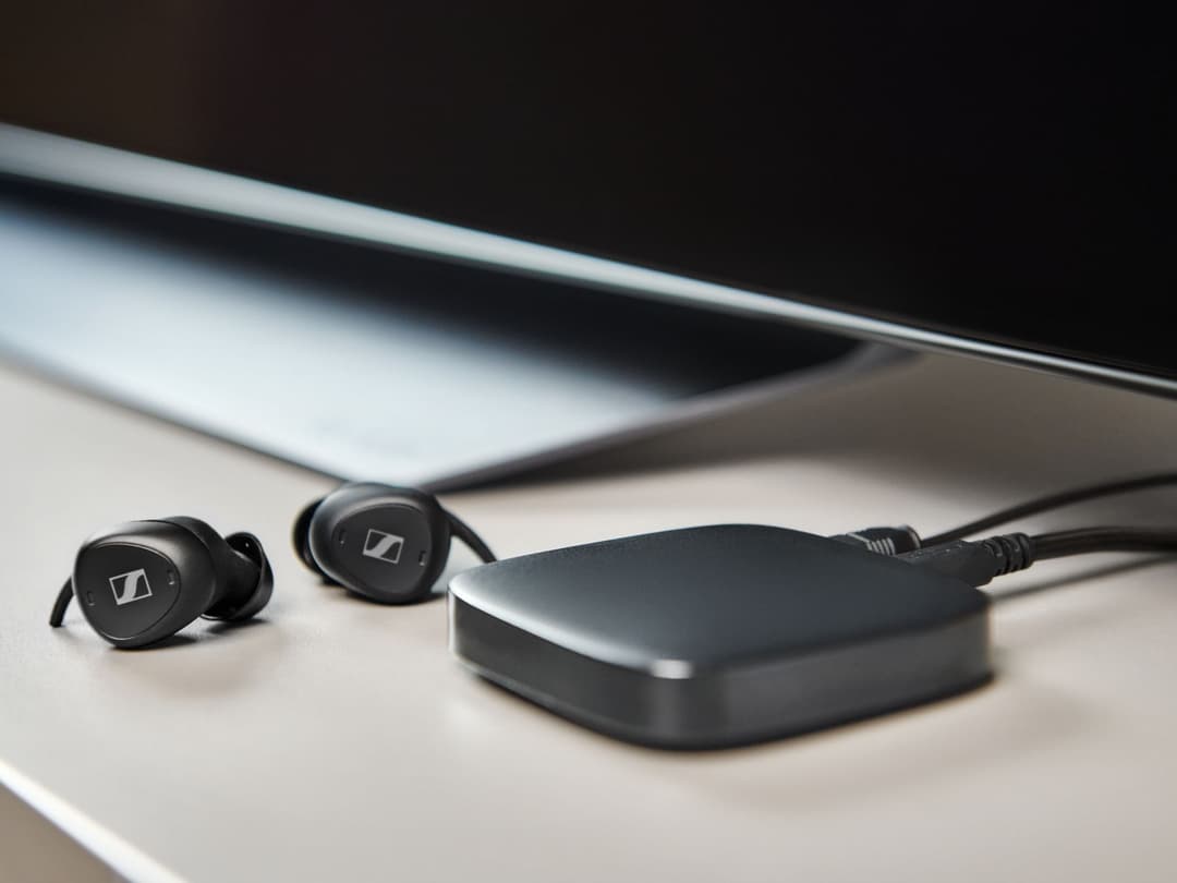 Écouteurs intra-auriculaires noirs avec boîtier de charge métallisé sur surface claire, écran en arrière-plan