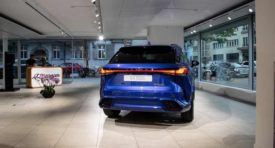 Lexus RX 500h bleu exposé dans le Lexus City Store de Zurich, espace moderne avec enseigne lumineuse