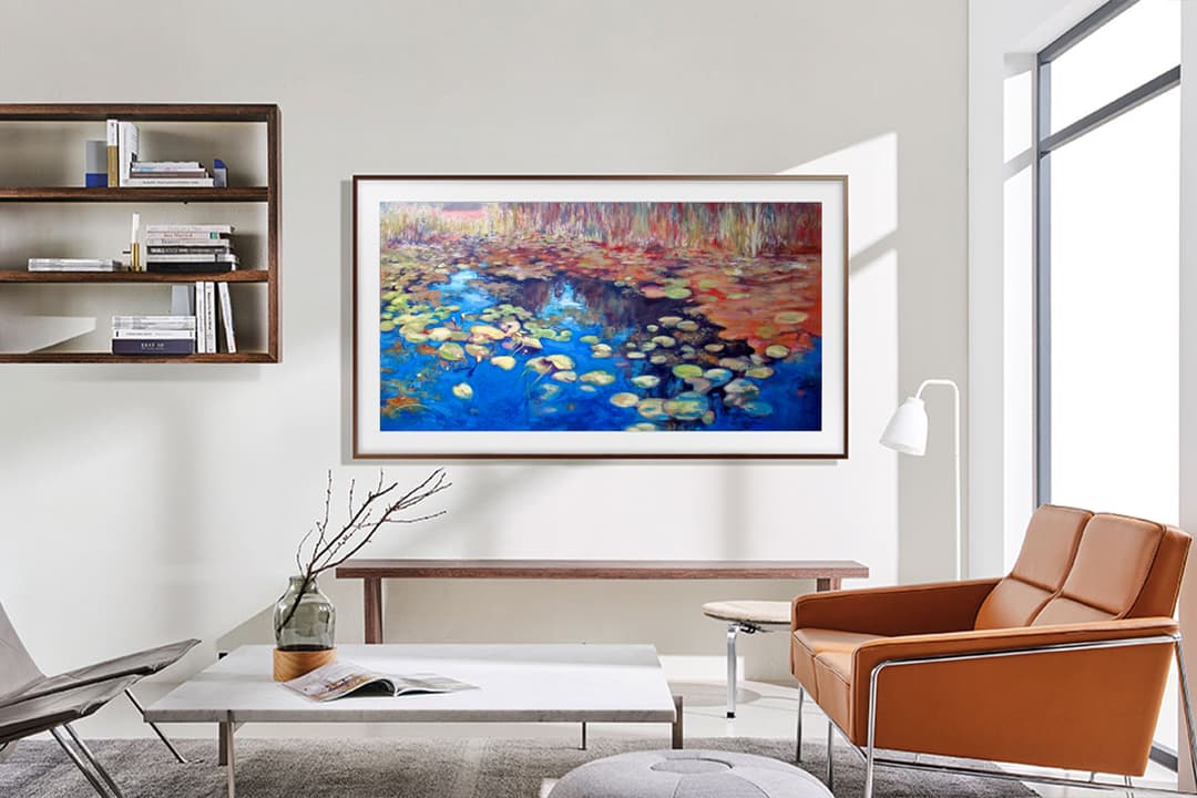 Projecteur Samsung The Freestyle affichant un paysage de nénuphars colorés sur un mur blanc d'un salon moderne avec fauteuil marron