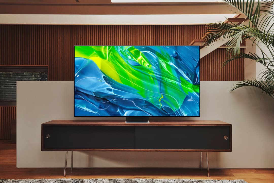 Téléviseur Samsung Neo QLED posé sur un meuble en bois, affichant des formes abstraites bleu et vert, dans un salon moderne