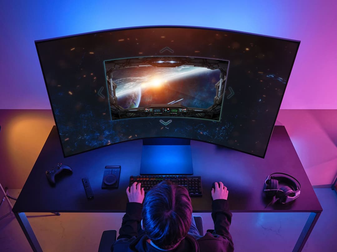 Écran incurvé Samsung OLED affichant une scène spatiale, installé au-dessus d'un bureau de gaming aux éclairages bleus et roses