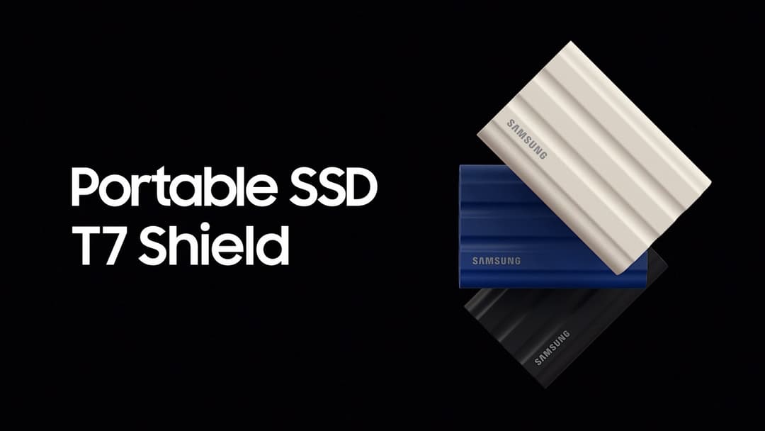 Trois disques SSD portables Samsung T7 Shield empilés en blanc, bleu et noir sur fond noir