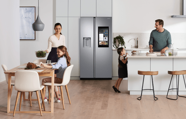 Cuisine moderne avec réfrigérateur Samsung BESPOKE gris, famille réunie autour d'une table en bois clair et d'un îlot central