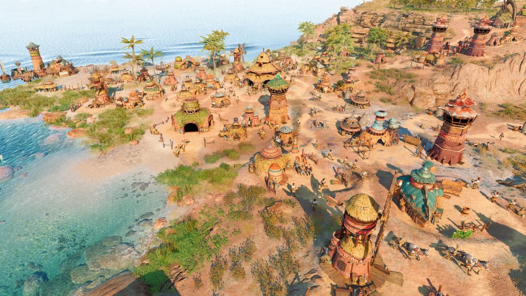 Capture d'écran de The Settlers New Allies montrant une colonie côtière avec bâtiments de terre cuite, habitants et tours de guet au bord d'une mer turquoise