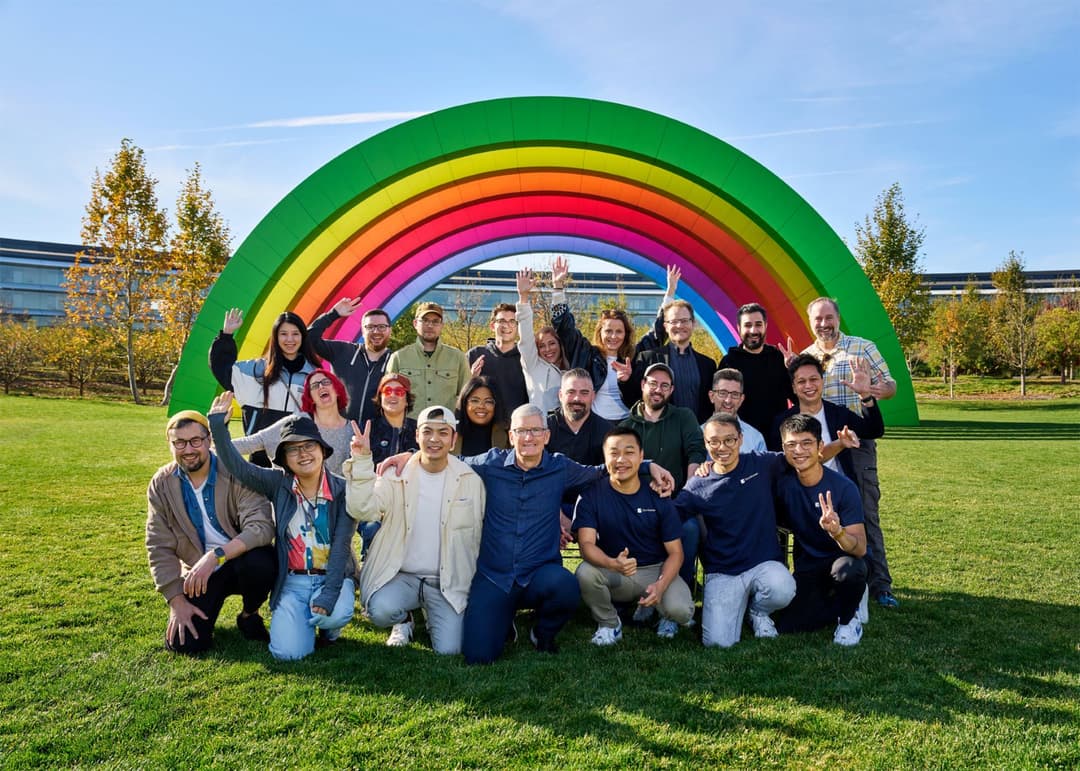 Tim Cook et l'équipe éditoriale de l'App Store posant devant une arche arc-en-ciel colorée sur une pelouse
