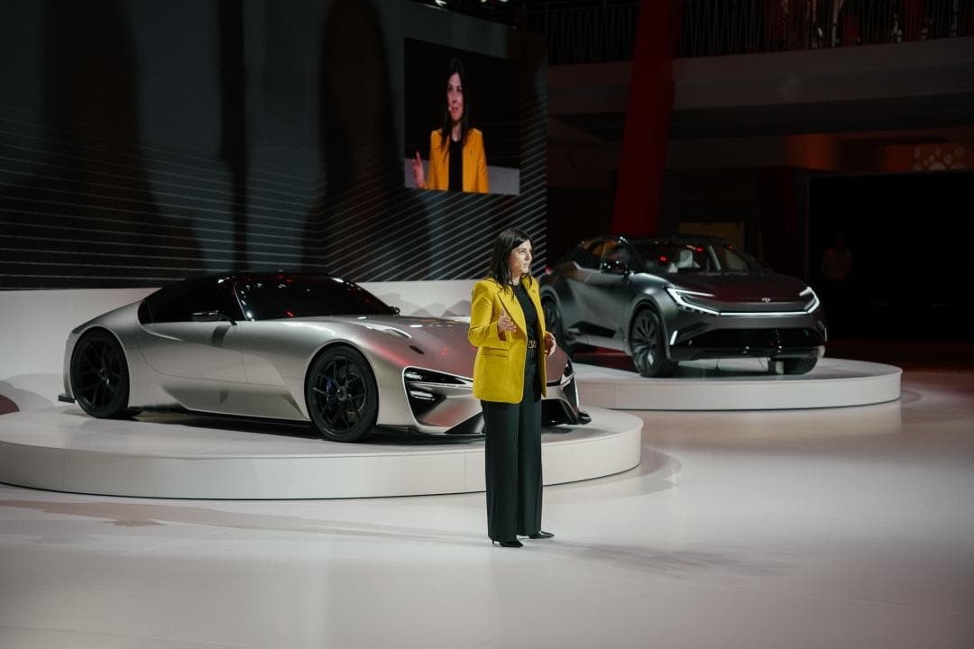 Kylie Jimenez en veste jaune présente des véhicules Toyota concept sur un podium lors d'un salon automobile