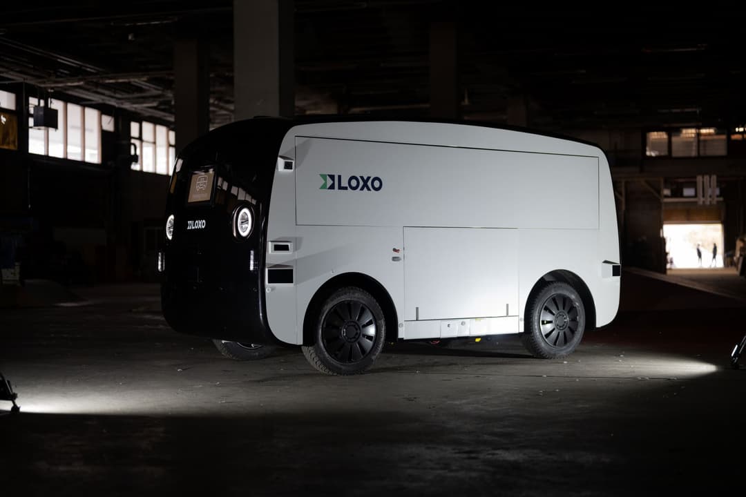 LOXO, robot de livraison autonome blanc et noir, garé dans un parking souterrain éclairé