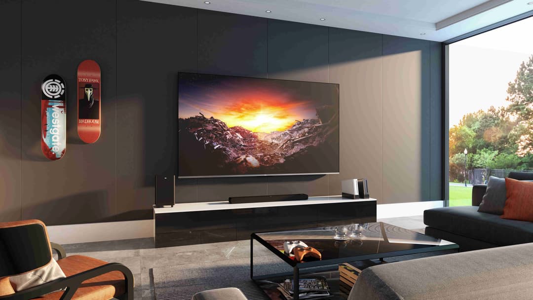 Téléviseur TCL C73 affichant un coucher de soleil montagneux, installé dans un salon moderne avec mobilier design