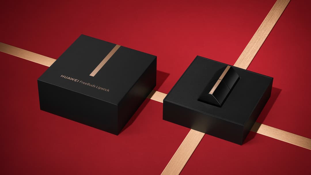 Boîtier de présentation noir des HUAWEI FreeBuds Lipstick ouvert, révélant les écouteurs, sur fond rouge avec bandes dorées