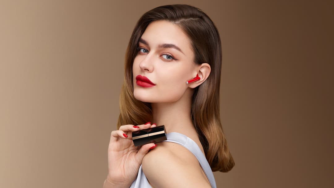 Femme portant les écouteurs HUAWEI FreeBuds Lipstick rouges en tenant l'étui de chargement noir et doré dans sa main