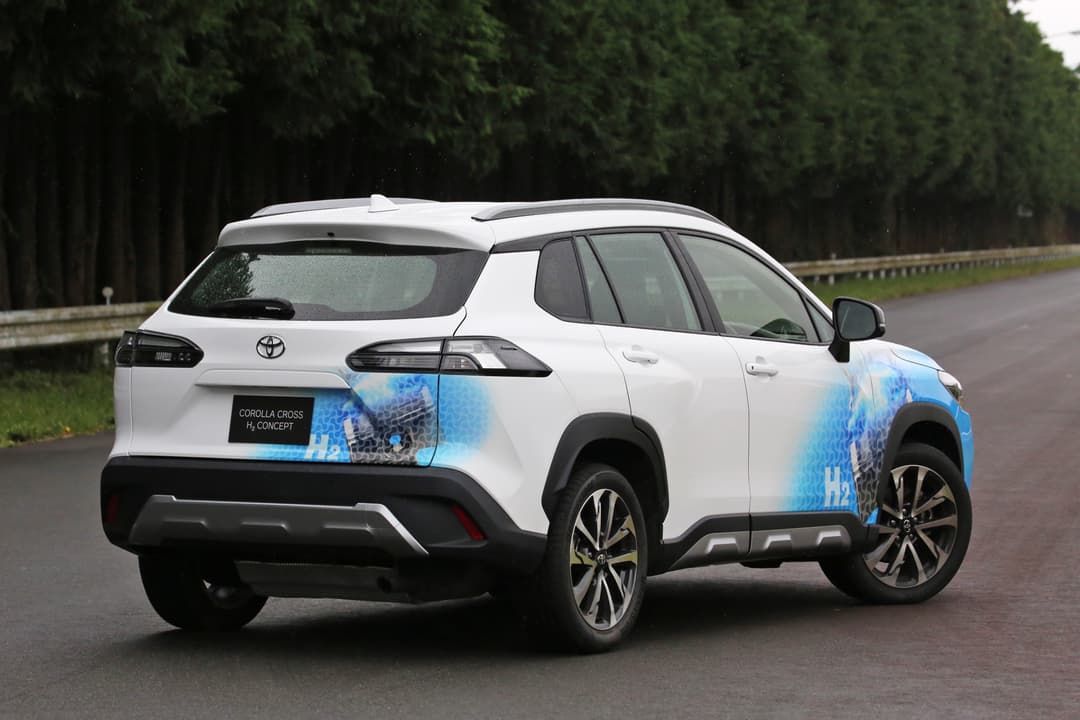 Prototype Toyota Corolla Cross à hydrogène blanc et bleu, garé sur une route forestière, vue de profil