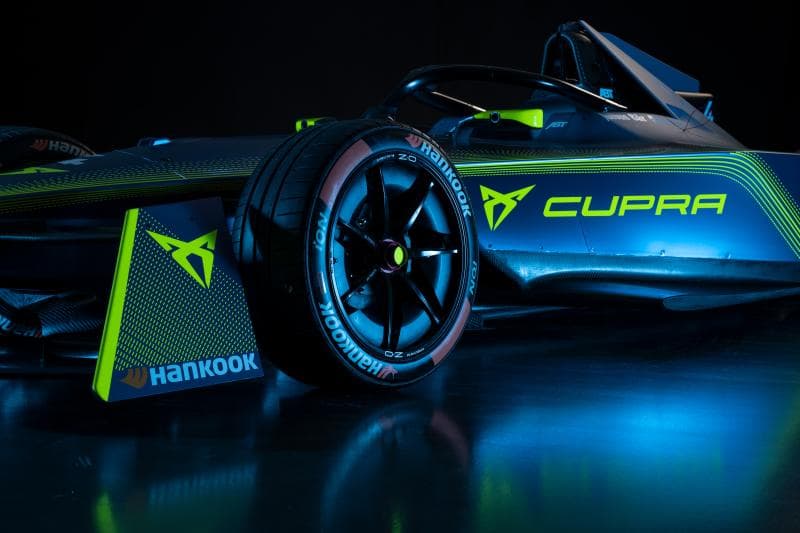 Monoplace de Formule E Cupra bleue et jaune fluo, vue de profil sur fond noir, avec le logo Cupra et les inscriptions des partenaires