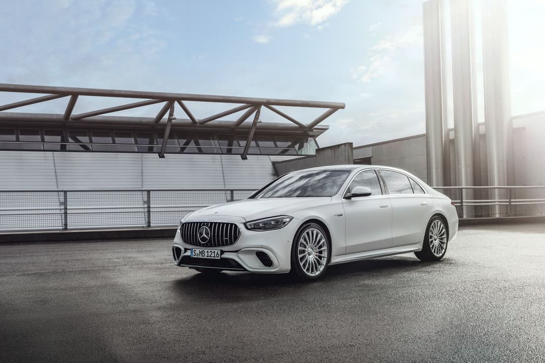 Mercedes-AMG S 63 E PERFORMANCE blanche de profil sur un parking, bâtiments industriels en arrière-plan