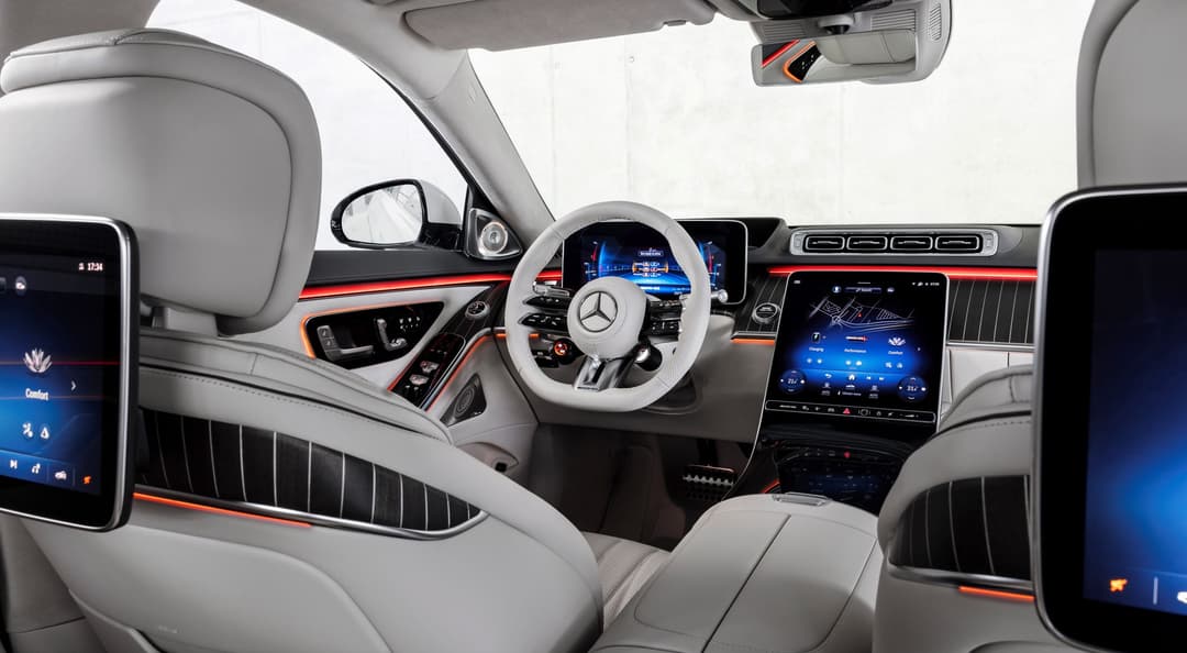 Intérieur de la Mercedes-AMG Classe S hybride avec volant blanc, sièges gris clair et bandes décoratives rouges sur la planche de bord