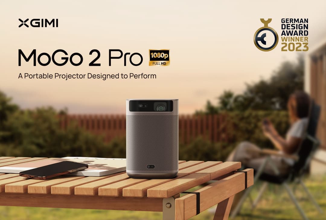 MoGo 2 Pro, projecteur portable gris clair au design cylindrique, posé sur une table en bois en extérieur, lauréat du German Design Award 2023