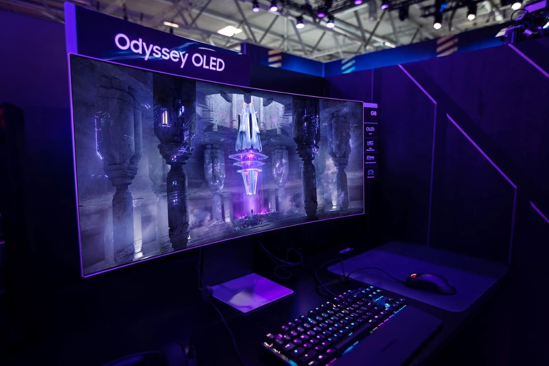 Moniteur Odyssey OLED G8 affichant un paysage futuriste en nuances de bleu et violet, installé dans un espace gaming avec clavier et souris