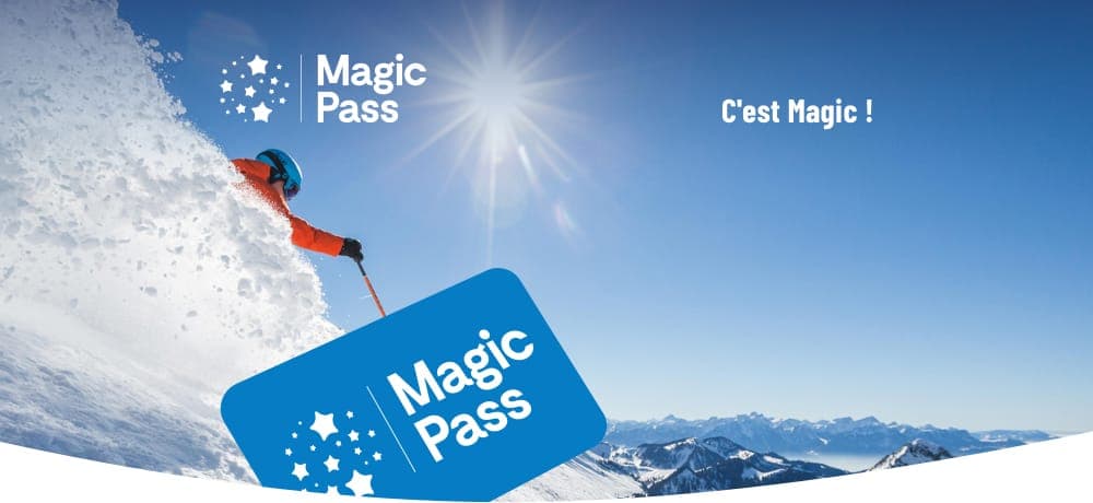 Skieur en vêtements rouges dévale une pente enneigée sous le soleil avec le logo et la carte Magic Pass en avant-plan