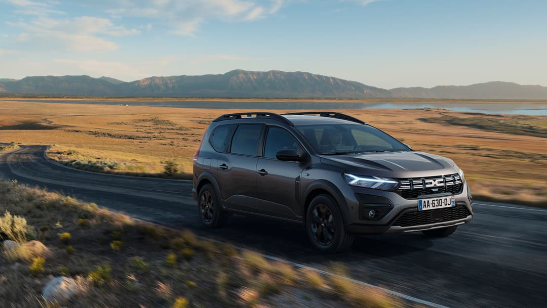 Dacia Jogger Hybrid 140 noir roulant sur une route de montagne désertique avec paysage de plateau à l'arrière-plan
