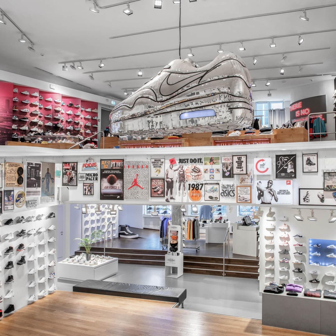 Intérieur du magasin Titolo à Zurich avec murs d'exposition de sneakers, grande sculpture Nike en relief et affiches de marques de streetwear