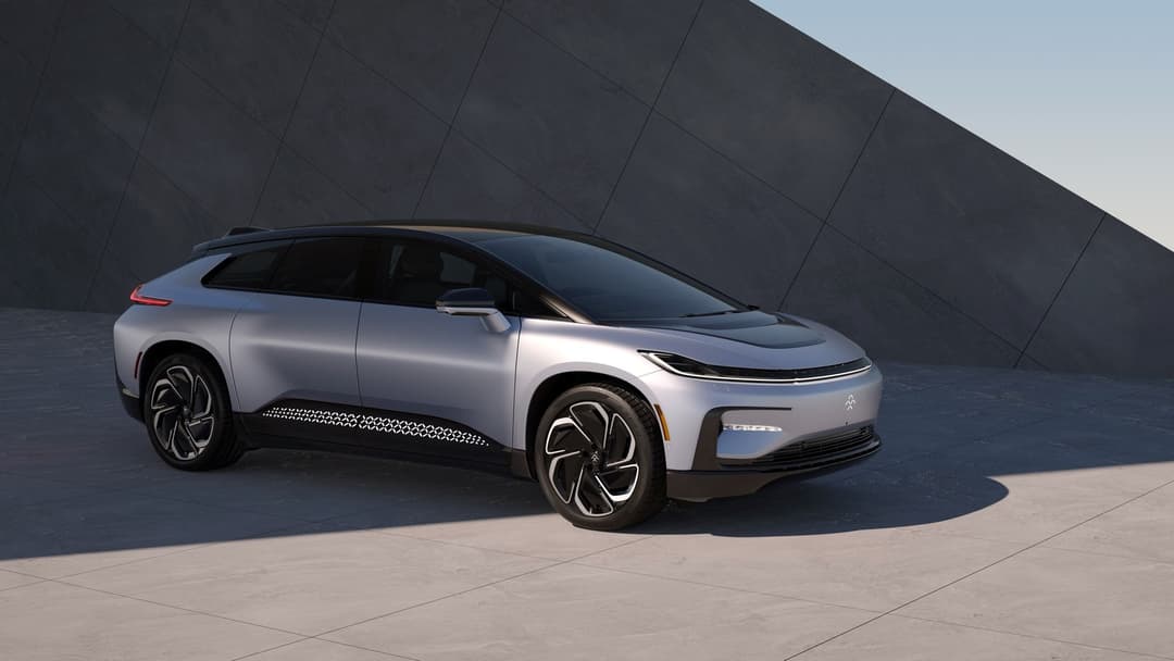 Faraday Future FF91, véhicule électrique blanc et noir de profil, devant un mur anthracite