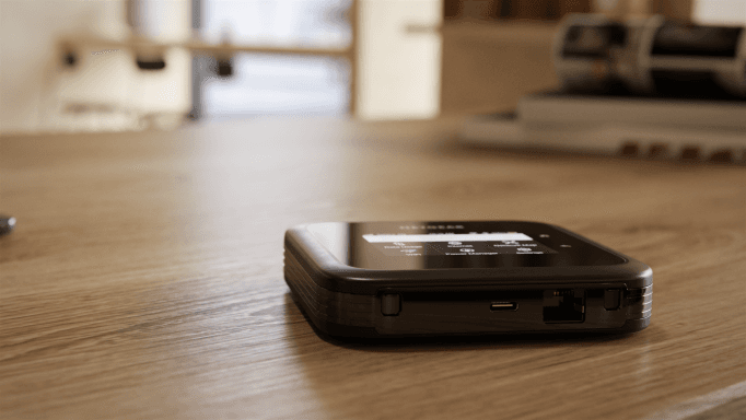 Routeur mobile Nighthawk M6 Pro noir posé sur un bureau en bois clair, vue de trois quarts