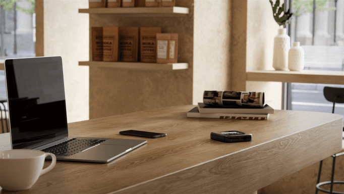 Routeur mobile Nighthawk M6 Pro noir posé sur un bureau en bois aux côtés d'un laptop et d'un smartphone