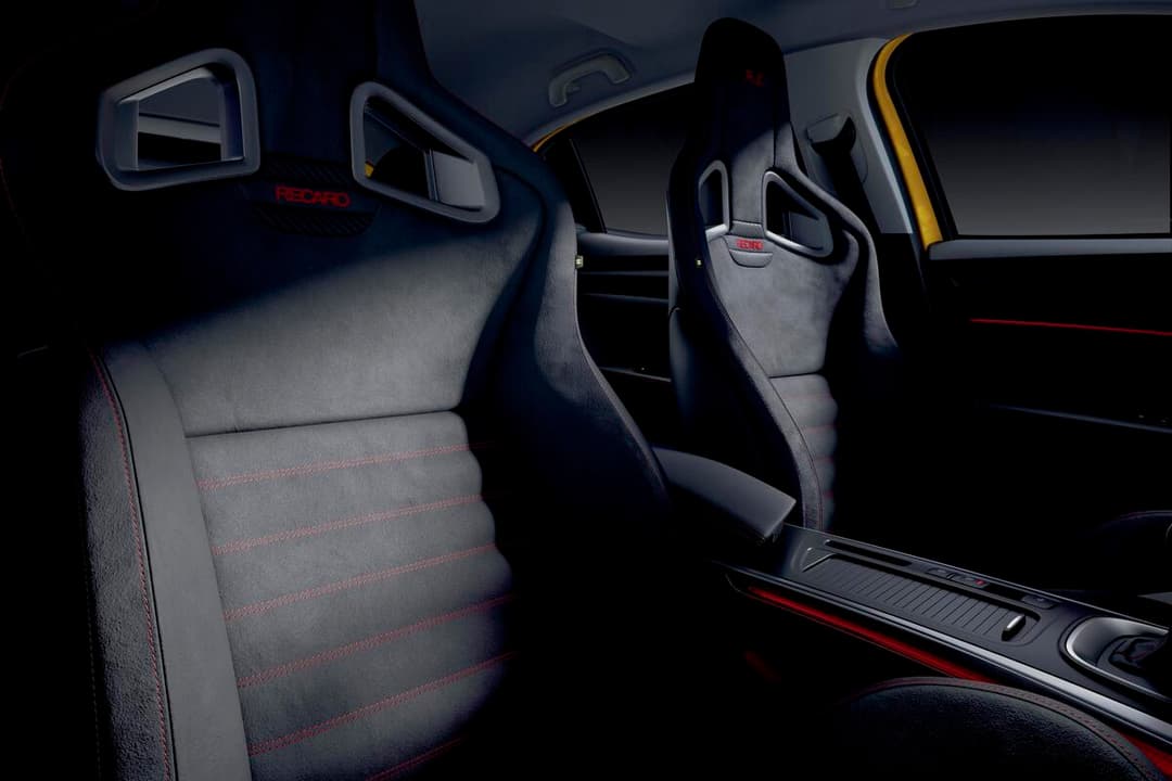 Intérieur de la Megane R.S. Ultime avec sièges Recaro gris et seuil de porte spécifique, plaque numérotée signée Laurent Hurgon près du levier de vitesses