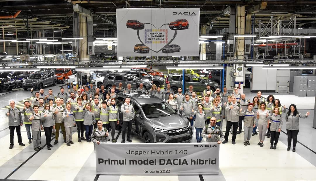 Dacia Jogger Hybrid 140 gris à l'usine de Mioveni avec l'équipe de production réunie autour du véhicule