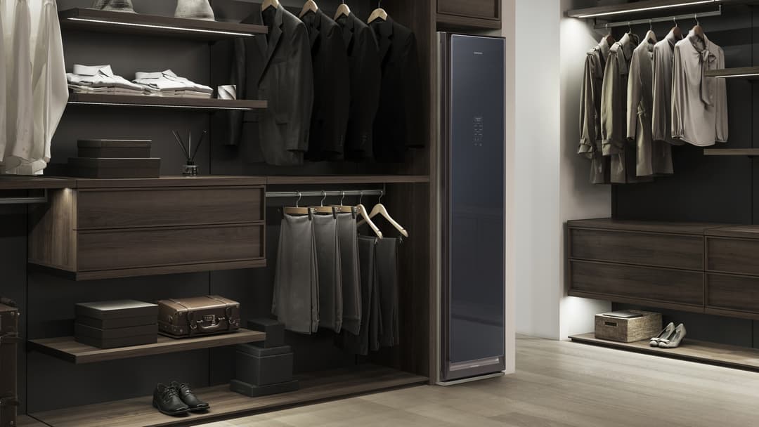 Samsung Bespoke AirDresser, armoire verticale noire et grise, entourée de vêtements sur cintres dans un dressing moderne et épuré