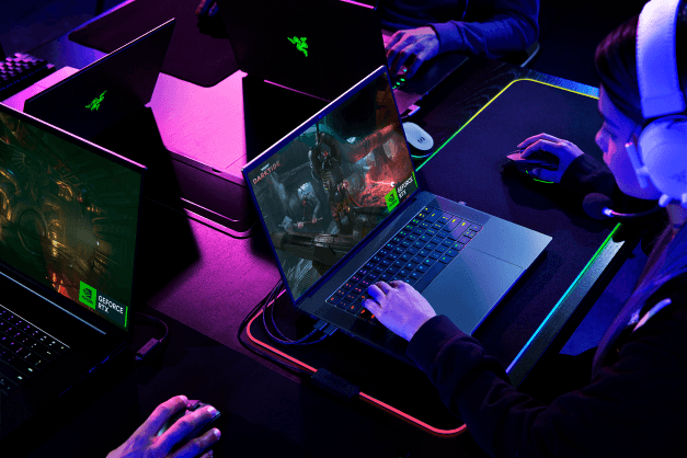 Razer Blade 16 portable gaming avec écran affichant un jeu vidéo, éclairage RGB magenta et bleu