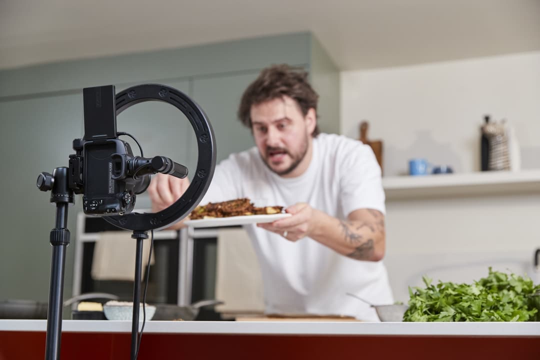 Créateur de contenu filmant un plat de nourriture avec un Canon EOS R50 et anneau lumineux en studio de cuisine