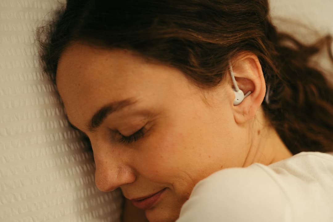 Femme portant un casque Philips blanc en écouteur, endormie contre un oreiller